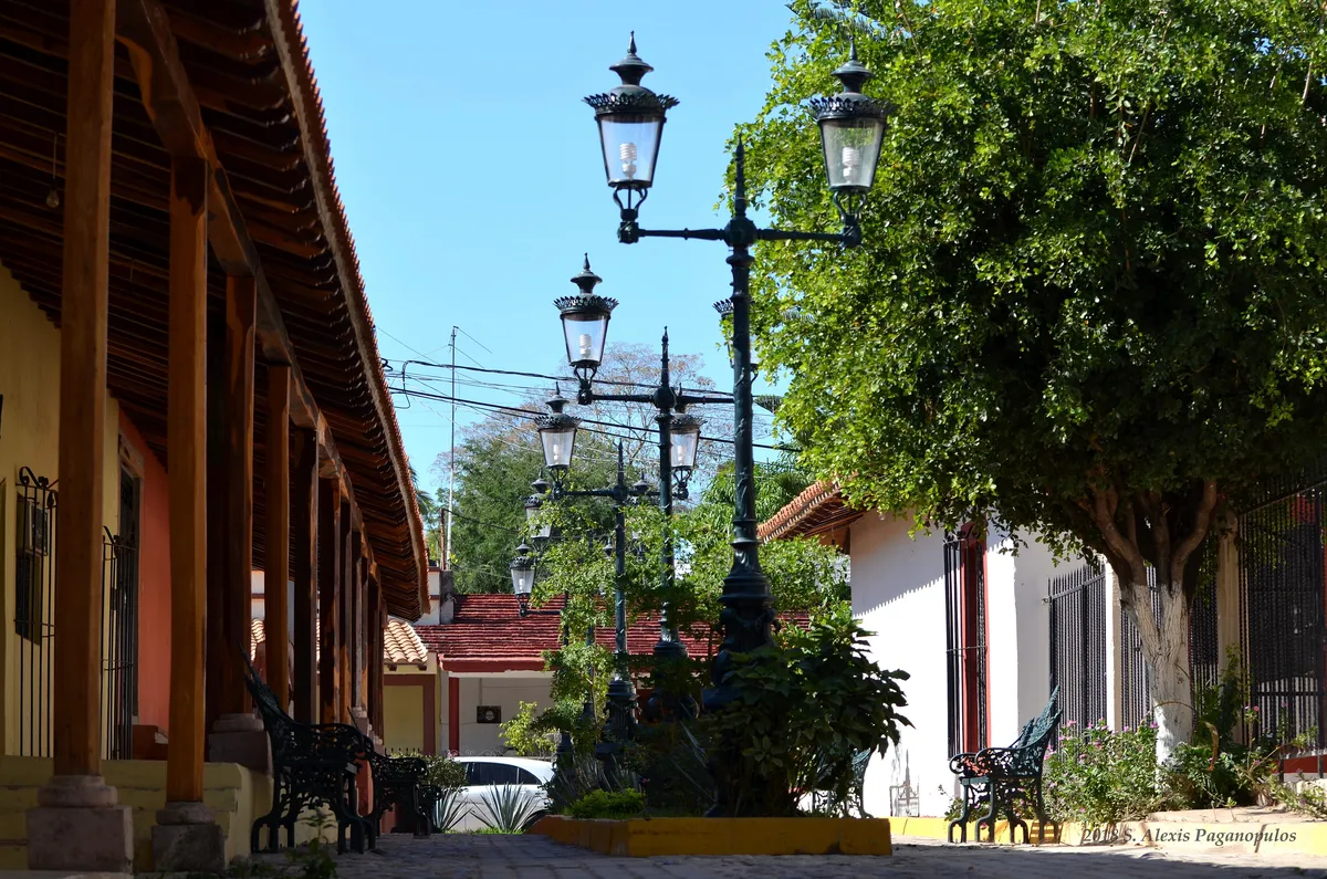 Cobbled street in El Quelite with whitewashed houses and tile-roofed arcades.